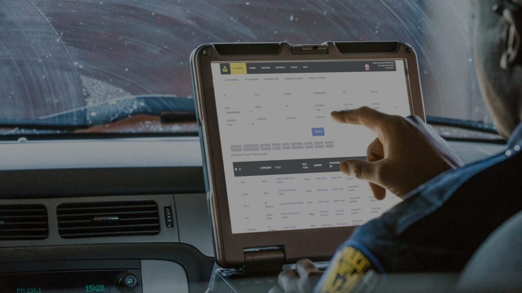 An American Police Officer working with AXON Evidence on a laptop whilst sitting in a car.